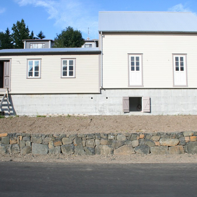 Hlaðinn steinveggur liggur bæði fyrir framan húsin sem og fyrir aftan þau